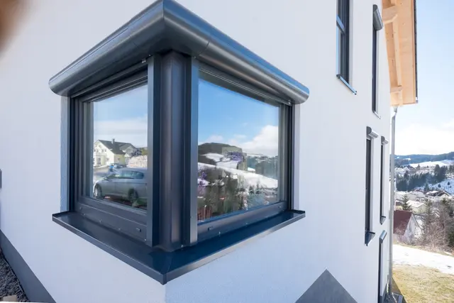 Anthrazitfarbenes Eckfenster mit Landschaftsspiegelung