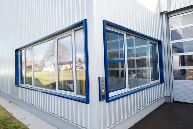 Eckfenster mit blauer Rahmung an einer Metallfassade