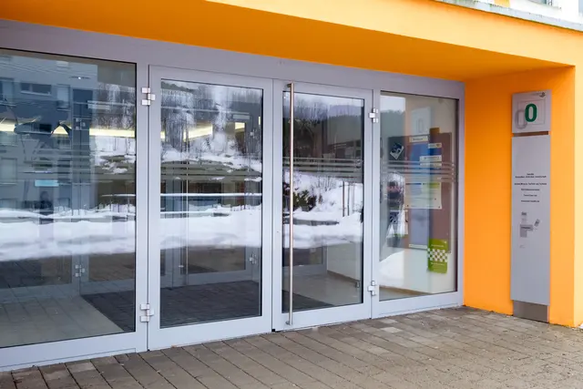 Verglaster Eingangsbereich mit orangefarbener Wand