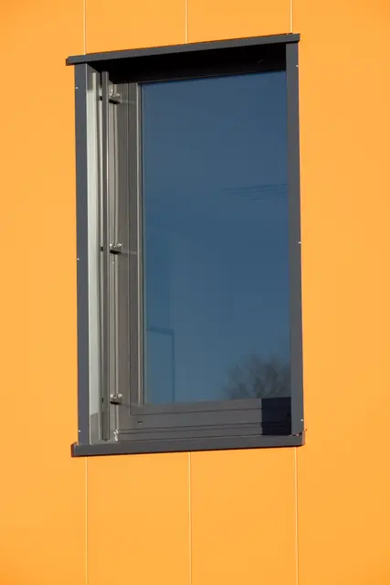 Dunkle Eingangstür in orangefarbener Gebäudefassade