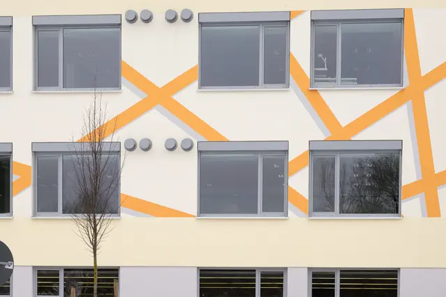 Fassade mit gelben Diagonalstreben und Fensterreihen