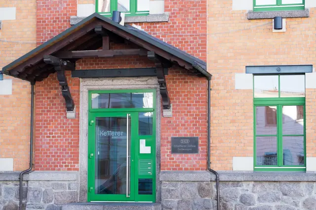 Grün gerahmtes Fenster in einer Klinkerfassade