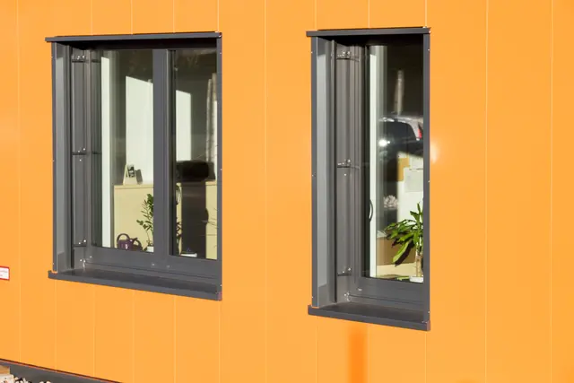 Fenster mit dunklen Rahmen in orangefarbener Fassade