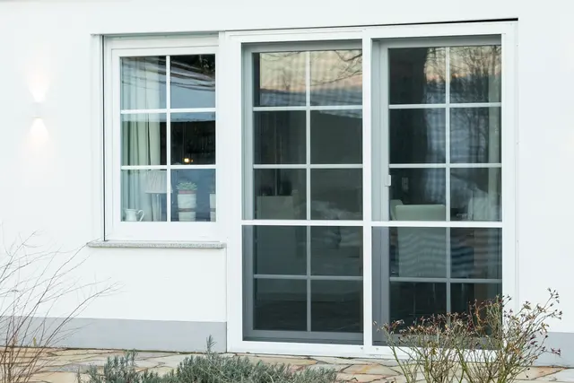 Weiße Fensterfront an einem verputzten Wohnhaus