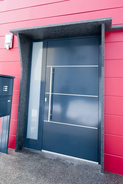 Moderne Haustür vor roter Fassadenverkleidung