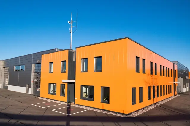 Gesamtansicht eines Neubaus mit orangefarbener Fassade