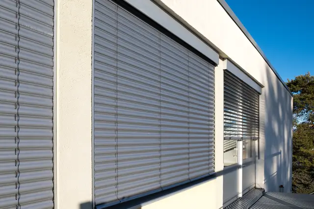 Außenliegende Raffstoren an einer dunklen Fassade